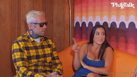 Adriana Chechik and Lena The Plug interview on orange couch in blue dress and yellow plaid shirt