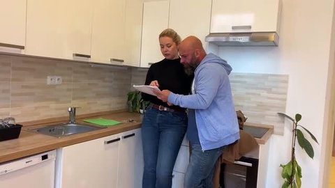 Blonde real estate agent in tight jeans and black top with client in kitchen