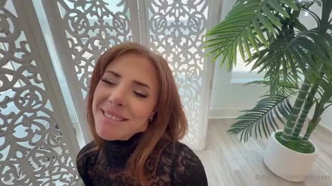 Lumi Ray in sheer black lace top smiling seductively