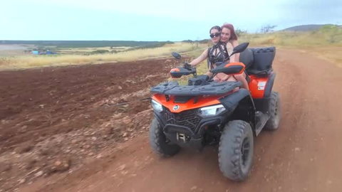 Dolly Dyson riding quad bike in bikini top and shorts outdoors