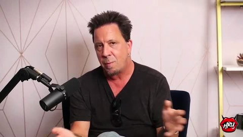 Mike Quasar interview in black V-neck shirt, podcast setup
