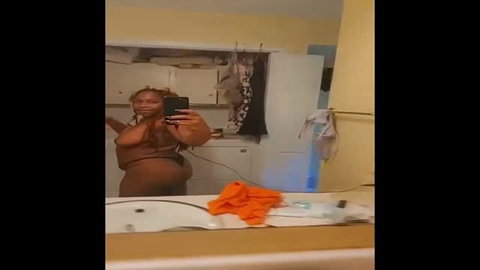 Sexy ebony woman in brown bodysuit taking mirror selfie
