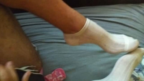 Man's feet in white socks receiving vibrator stimulation during condom handjob