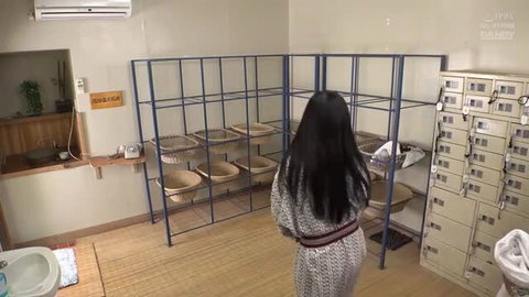 Japanese woman with long black hair in patterned dress standing in locker room