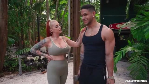 Cubbi Thompson in green sports bra and leggings with muscular man outdoors