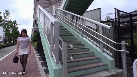 Asahi Mizuno in tight white dress and black stockings walking by outdoor stairs