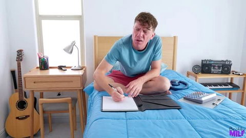 Rion King in teal shirt on bed writing notes, Bratty Milf scene