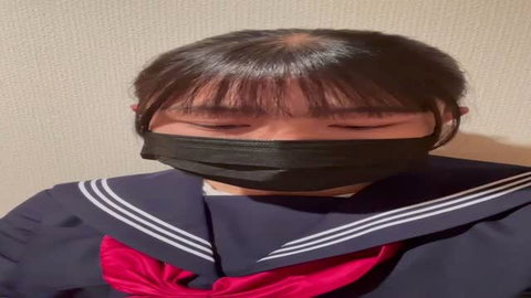 Asian schoolgirl in sailor uniform with black tape gag, teasing expression
