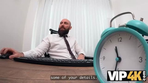 Bald bearded man in white shirt at desk with huge teal alarm clock