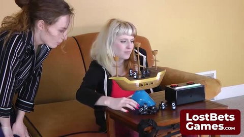 Two women in striped blazer and red top play pirate-themed Lost Bets Games with toy ship