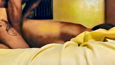 Muscular black man lying nude on bed, tattooed back and side view