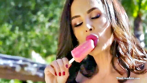 Lisa Ann seductively licks pink popsicle in teasing solo outdoor scene