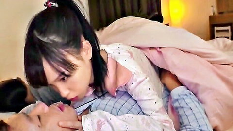 Cute petite Asian girl in pink pajamas straddling and kissing man intimately