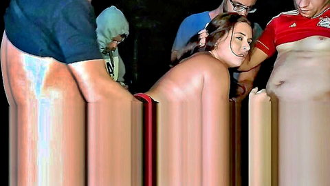 Brunette woman topless in outdoor gangbang with multiple clothed men at night