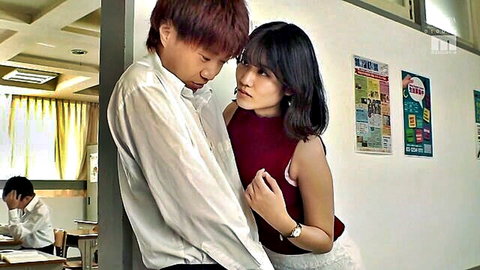 Japanese schoolgirl in maroon tank top and white skirt intimately close to classmate against classroom wall