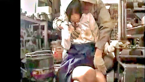 Asian schoolgirl in uniform restrained by gloved man in workshop