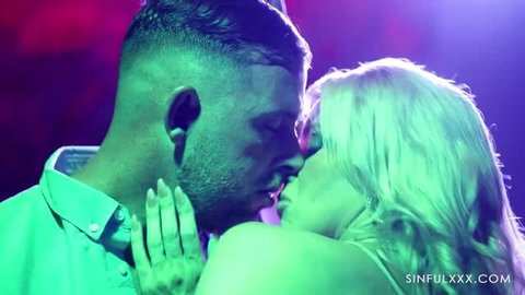 April Paisley in sensual close-up kiss with male partner under neon lights