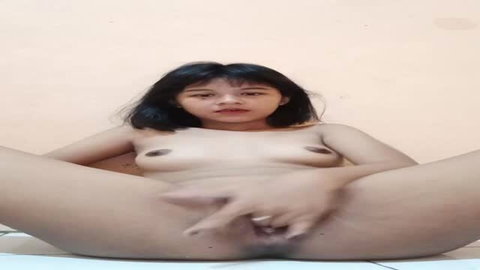 Asian woman spreads legs fingering pussy on floor