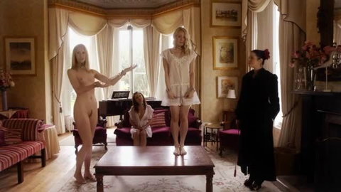 Femdom domina dominates three bound blondes in living room scene