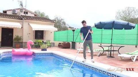 Mature woman in navy top cleaning pool outdoors at villa