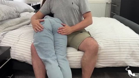Man in grey shirt holding partner on lap in jeans on bed