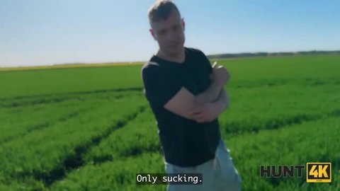 Man in black shirt standing in green field with arms crossed