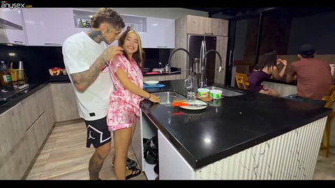 Amateur couple getting intimate in kitchen with friends nearby