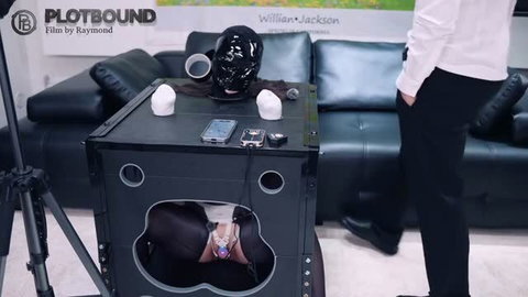 Black latex hooded submissive in BDSM box restraint