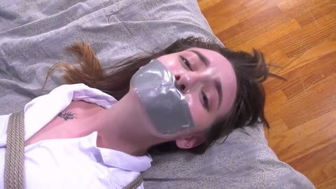 Woman gagged with duct tape and rope bound, lying on bed