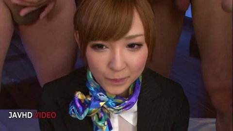 Hikaru Shiina in business suit with colorful scarf surrounded by cocks in gangbang scene