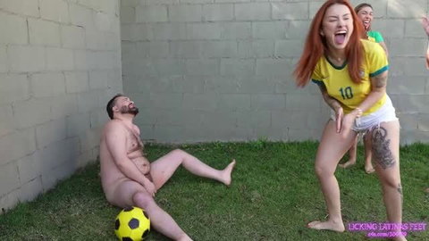 Redhead in Brazil jersey laughs while naked man sits by soccer ball