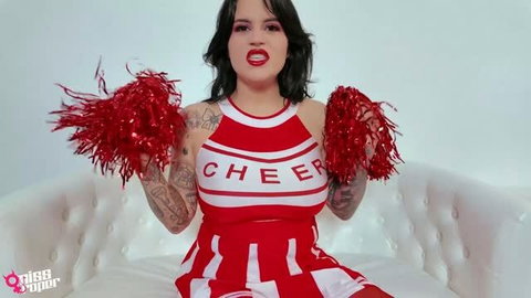 Miss Roper in red cheerleader outfit holding pom poms, feminization fantasy
