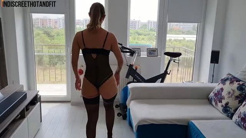 Woman in sheer black bodysuit and stockings standing in living room