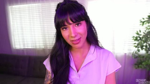 Sloane Sabbath in purple lighting wearing light purple top with bangs and long black hair