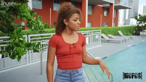 Curly-haired ebony babe in red top by poolside