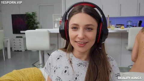 Brunette gamer girl with large headphones smiling in kitchen setting
