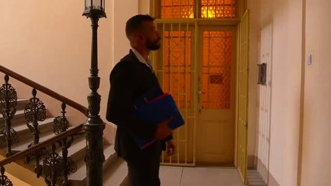 Man in suit carrying blue folder in hallway