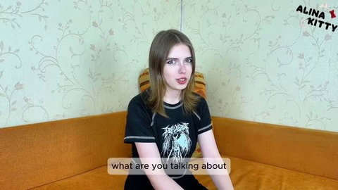 Alt girl in black graphic tee talking on couch