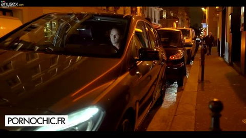 Man in car at night looking at camera on city street