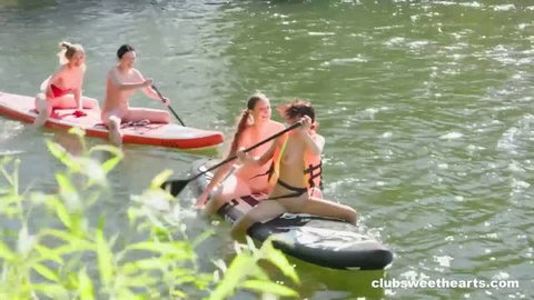Four young women paddleboarding topless outdoors