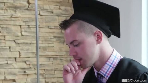 Young male graduate in cap and gown sucking finger