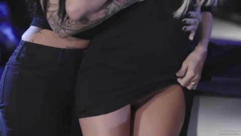 Jessica Drake and Jessie Lee in black dresses during passionate embrace