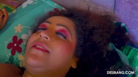 Curvy woman with curly hair and makeup lying on bed, close-up face shot