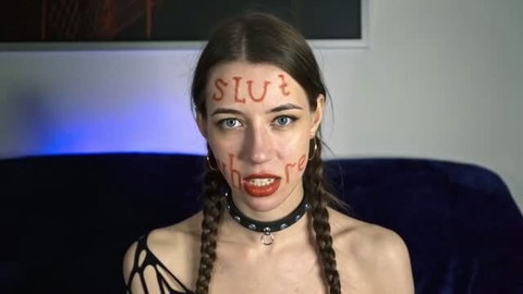 Brunette with pigtails and red lipstick, face written SLUT and whore, wearing black choker
