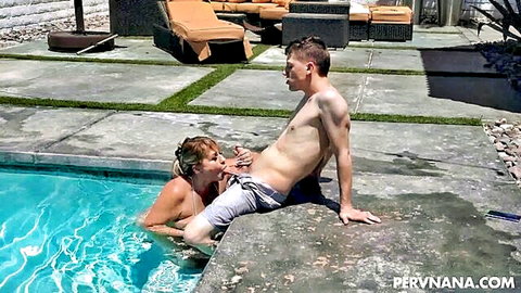 Busty blonde grandma performing oral on young man by pool edge