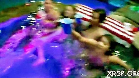 Bikini girls in glowing pool party with shirtless hunk, wild scene