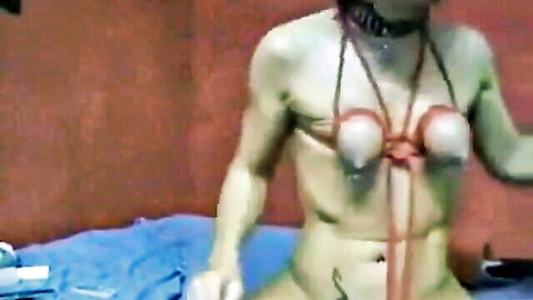Muscular woman in self-bondage with red ropes tying her tits