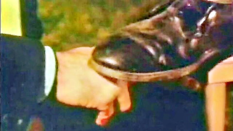 Man's hand pressing woman's black leather boot in fetish scene