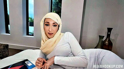 Sophia Sweet in hijab, seductive pose on bed in white outfit