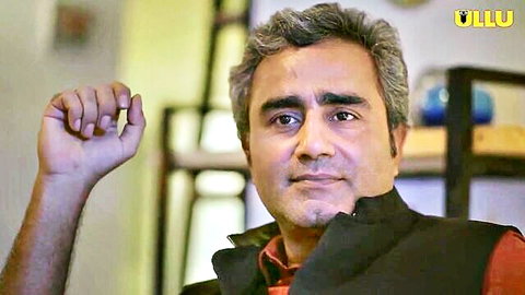 Mature Indian man smiling raising hand in black vest over red shirt